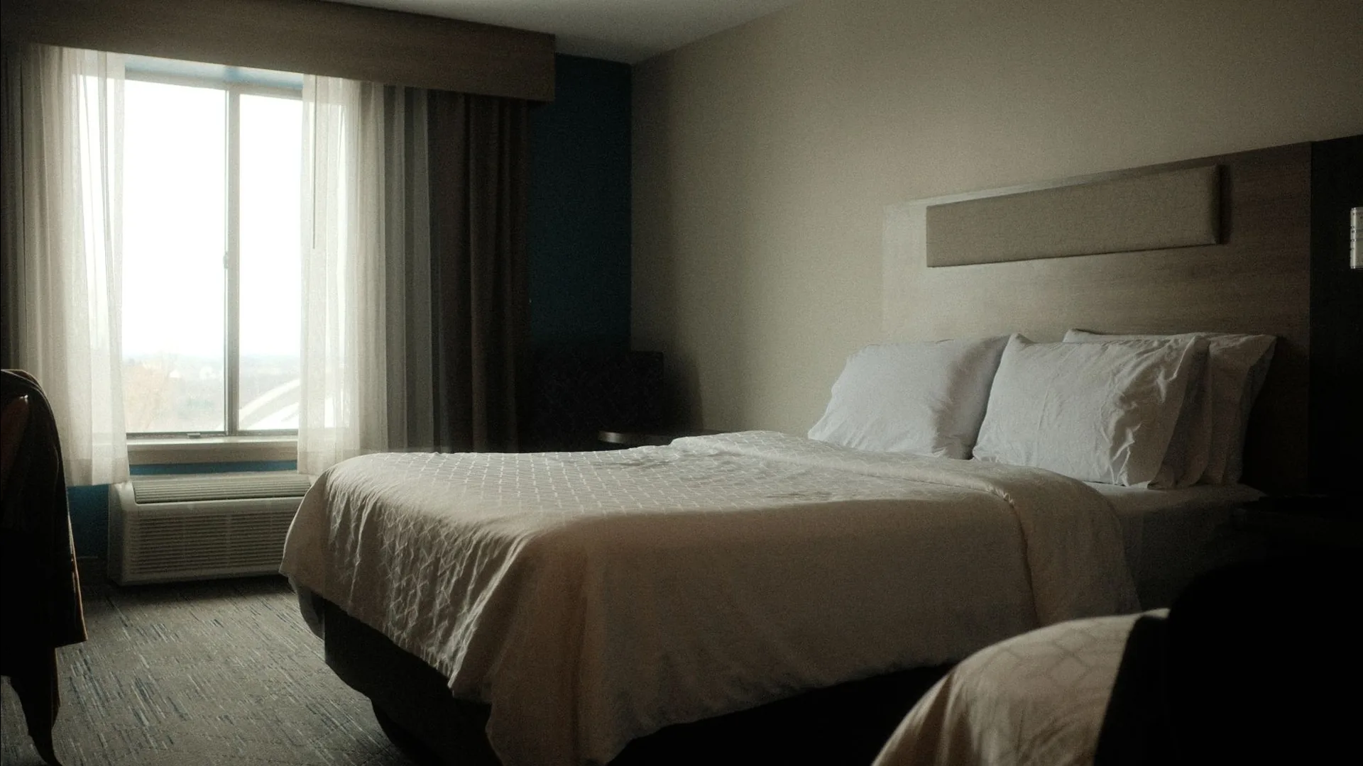 Hotel bedroom with morning light on white bedding